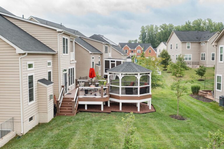 Distant view of 14' Octagon Vinyl Gazebo, in green grass, surrounded by neighboring houses