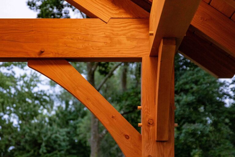 Pavilion lighting highlights interior corner of timber frame-trees in the distance at dusk