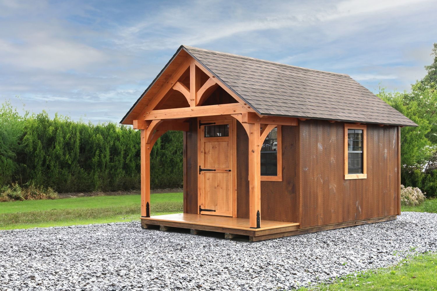 Brown Somerset Timber Frame Shed in Gravel lot with timber frame truss and porch. Two windows and single door