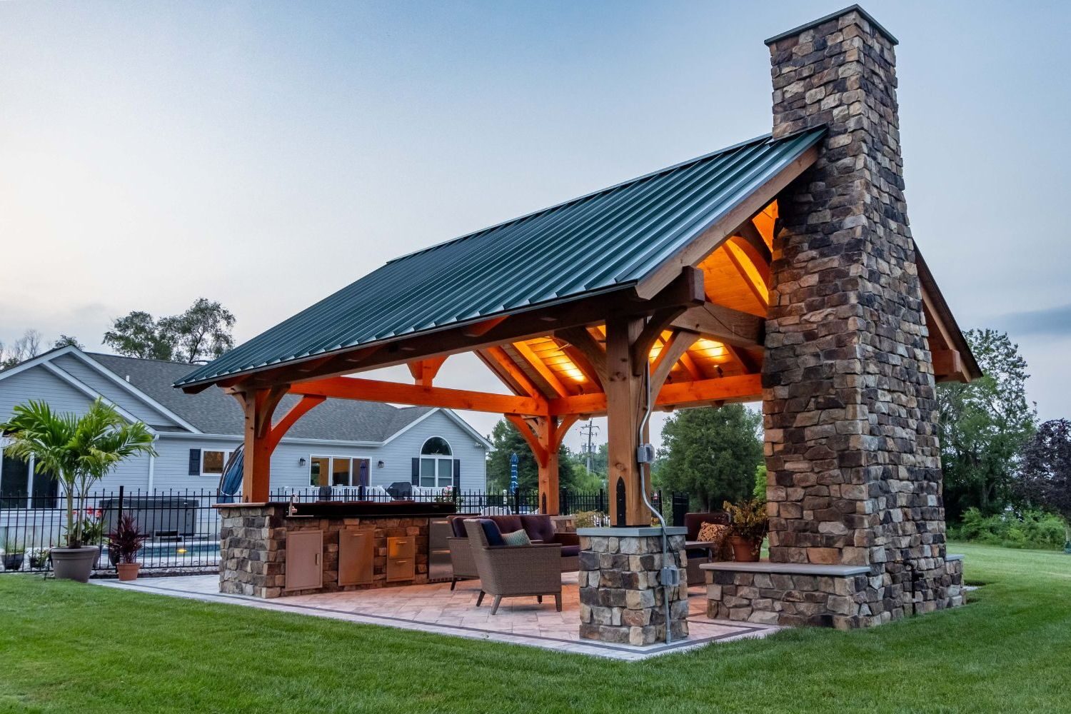 Timber Frame Pavilion with Chimney, Fireplace, and seating at Dusk