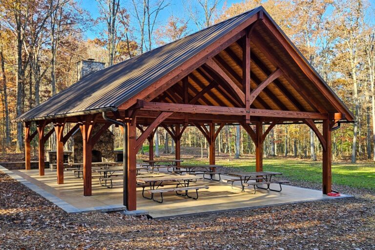 View of 30x50 Kingston Pro Timber Frame Pavilion in Mill Hall PA with fireplace and picnic tables underneath
