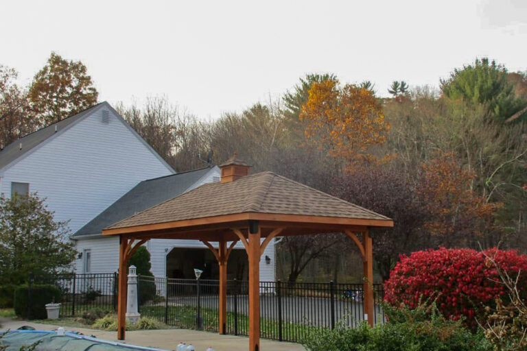 stained outdoor pavilion in front of a garage