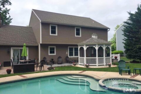 A Vinyl Gazebo By The Pool With Permanent Asphalt Shingles At The Backyard